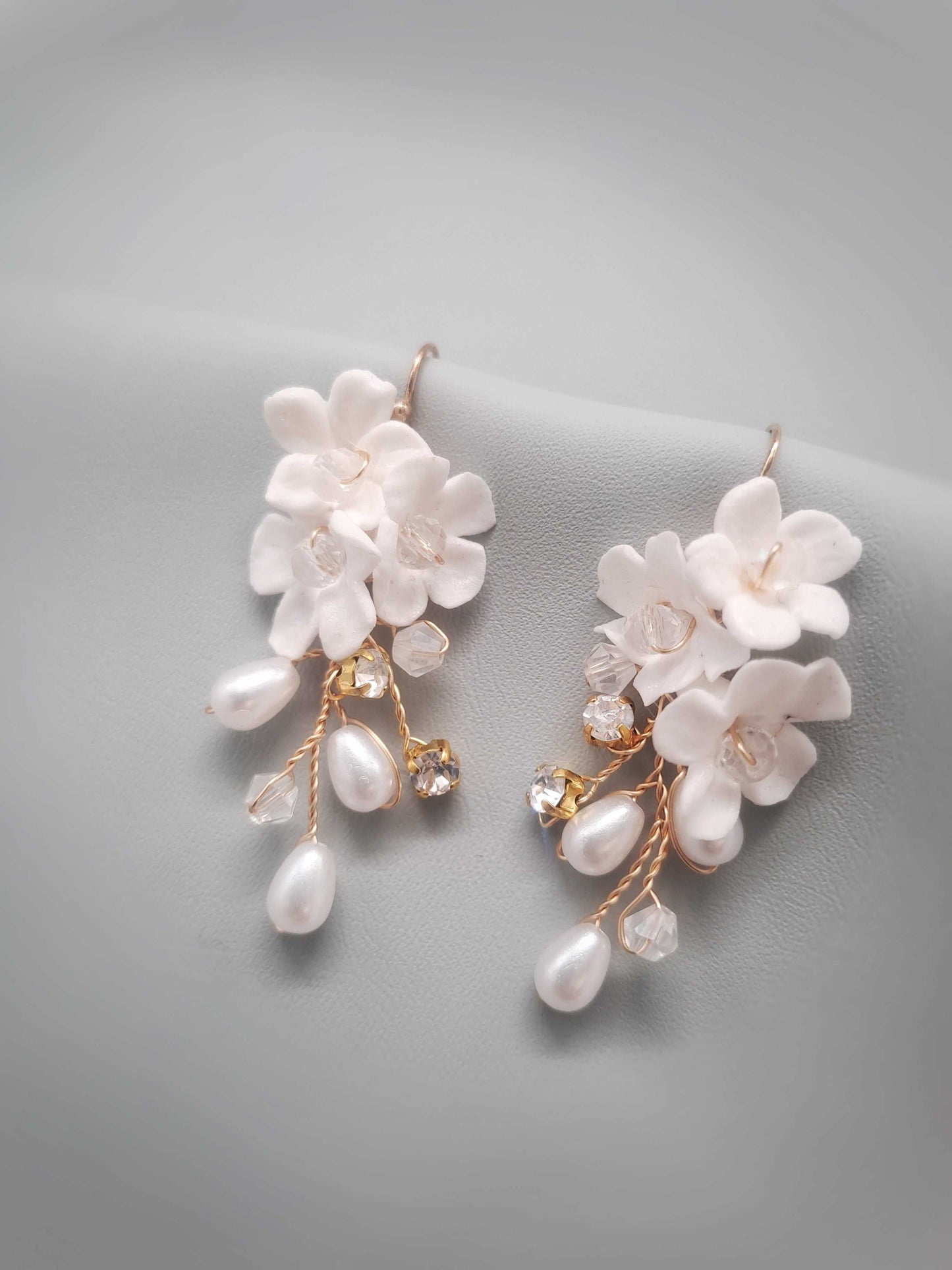 Pair of floral earrings with pearl accents on a gray background. Sienna Bridal Earrings