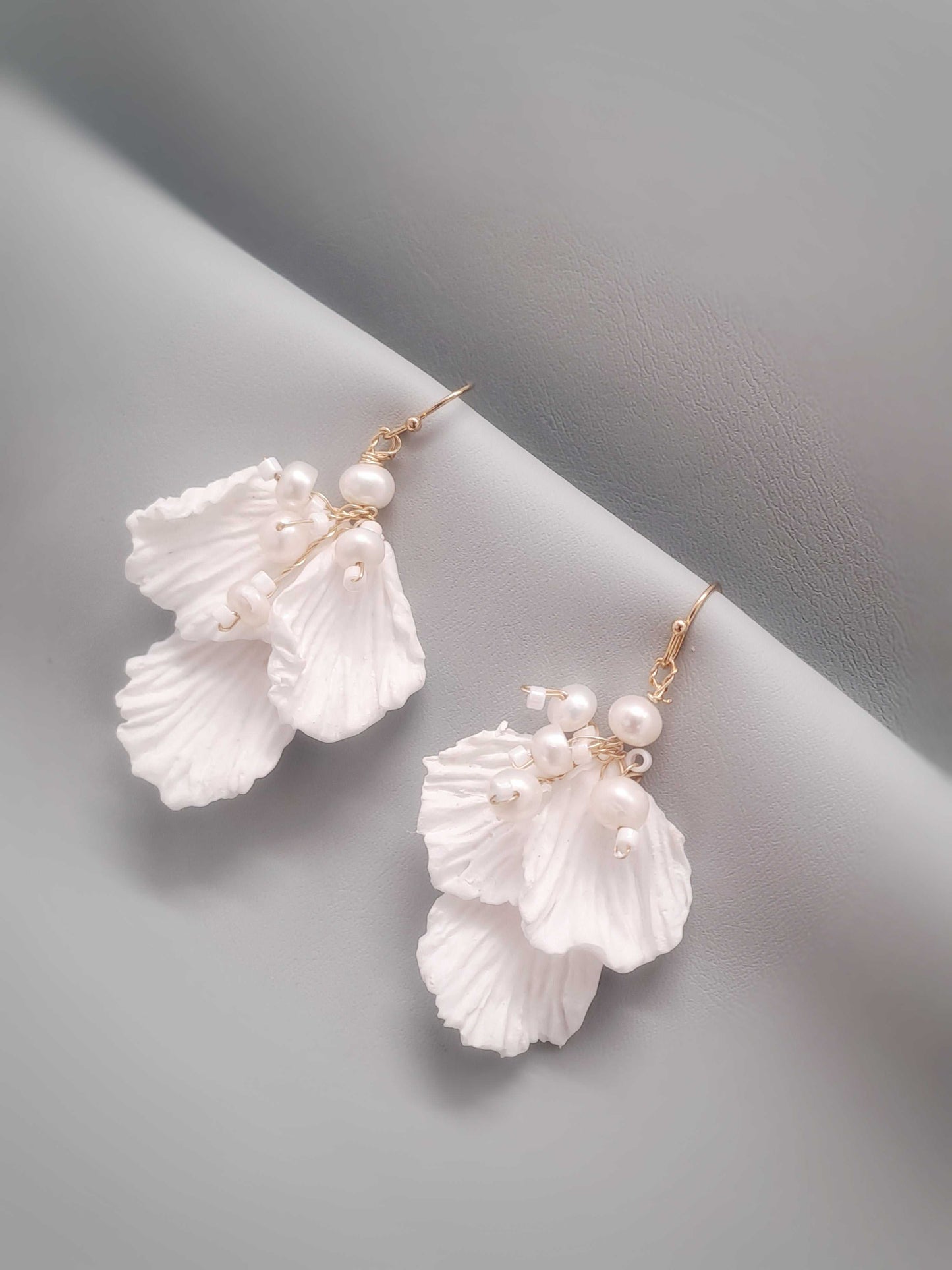 White floral earrings with pearl accents on a gray background