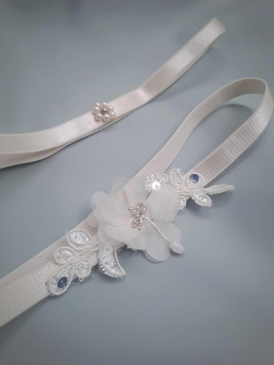 White garter set ith floral and lace details on a gray background