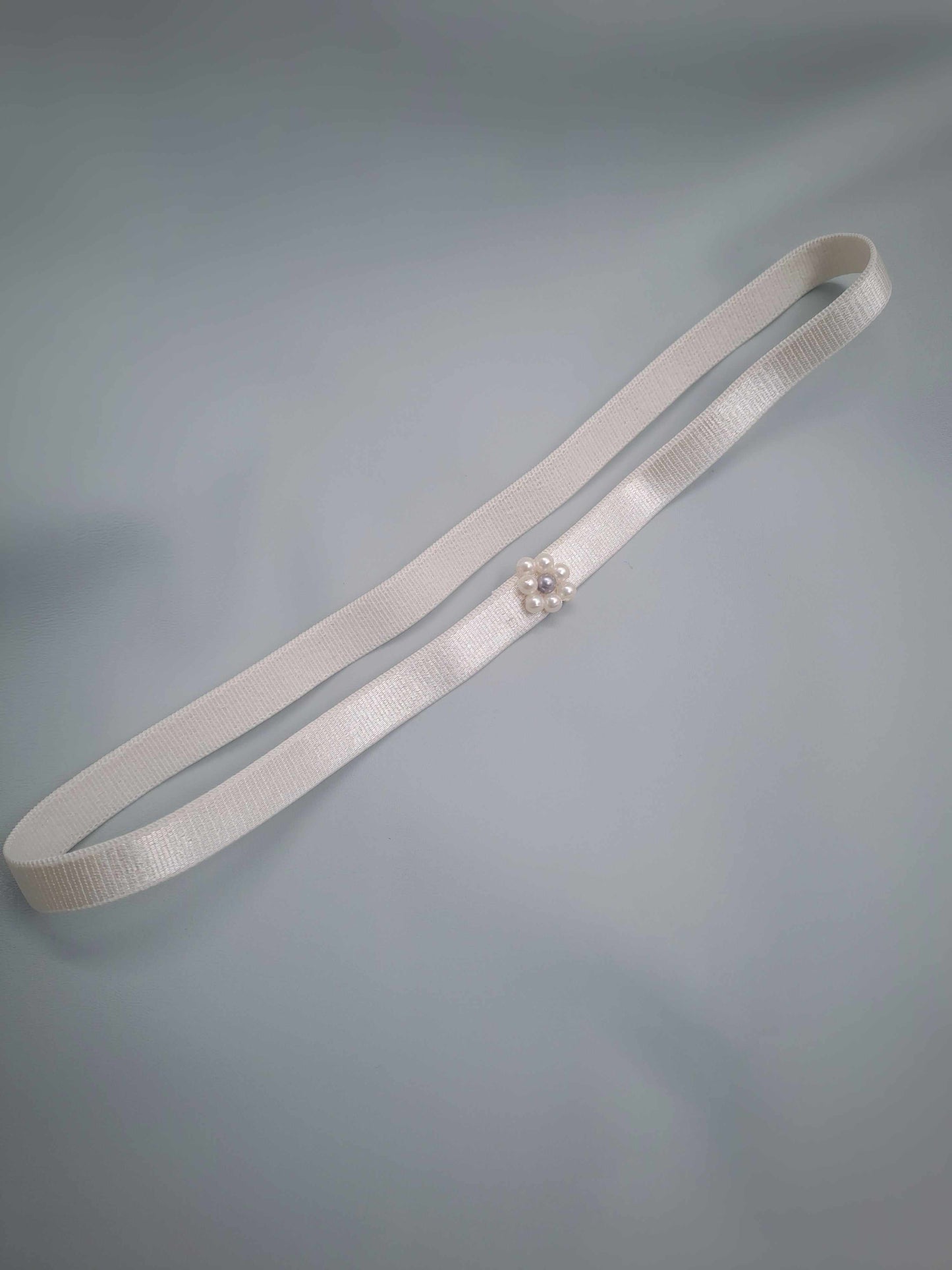 White garter with apearl embelishment on a gray background