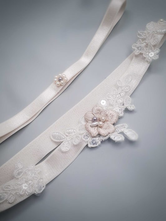 Bridal garter with floral embellishments on a gray background
