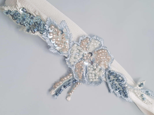Montrose heirloom wedding garter with hand-beaded champagne, blue, and sage floral design on white band