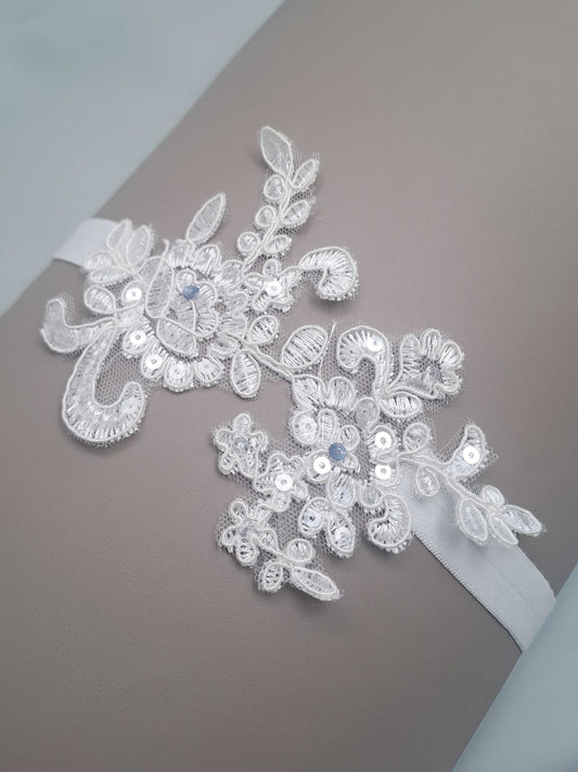 Decorative lace applique wedding garter with beads on a plain background