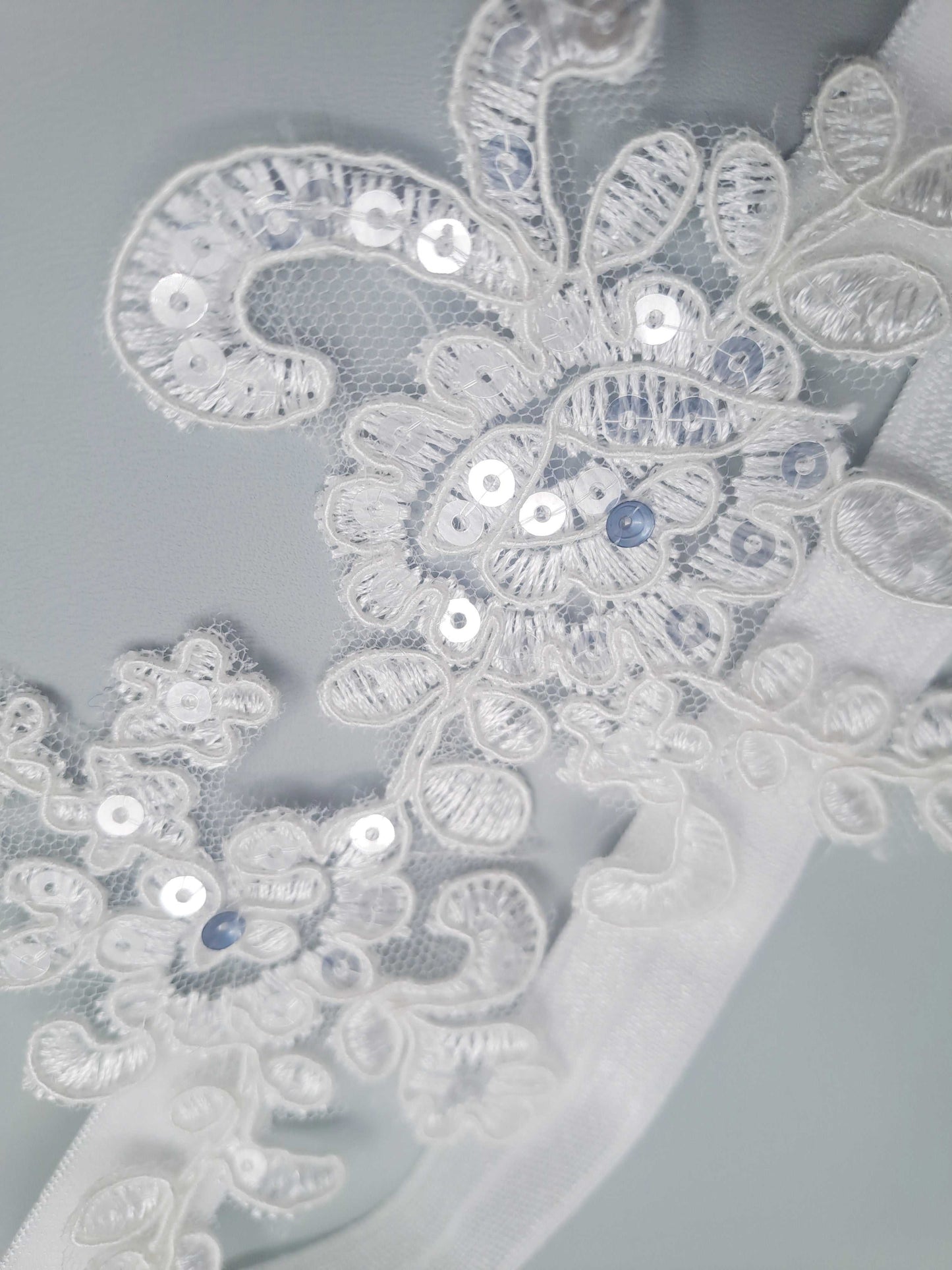 Close-up of intricate lace with sequins on a light gray background