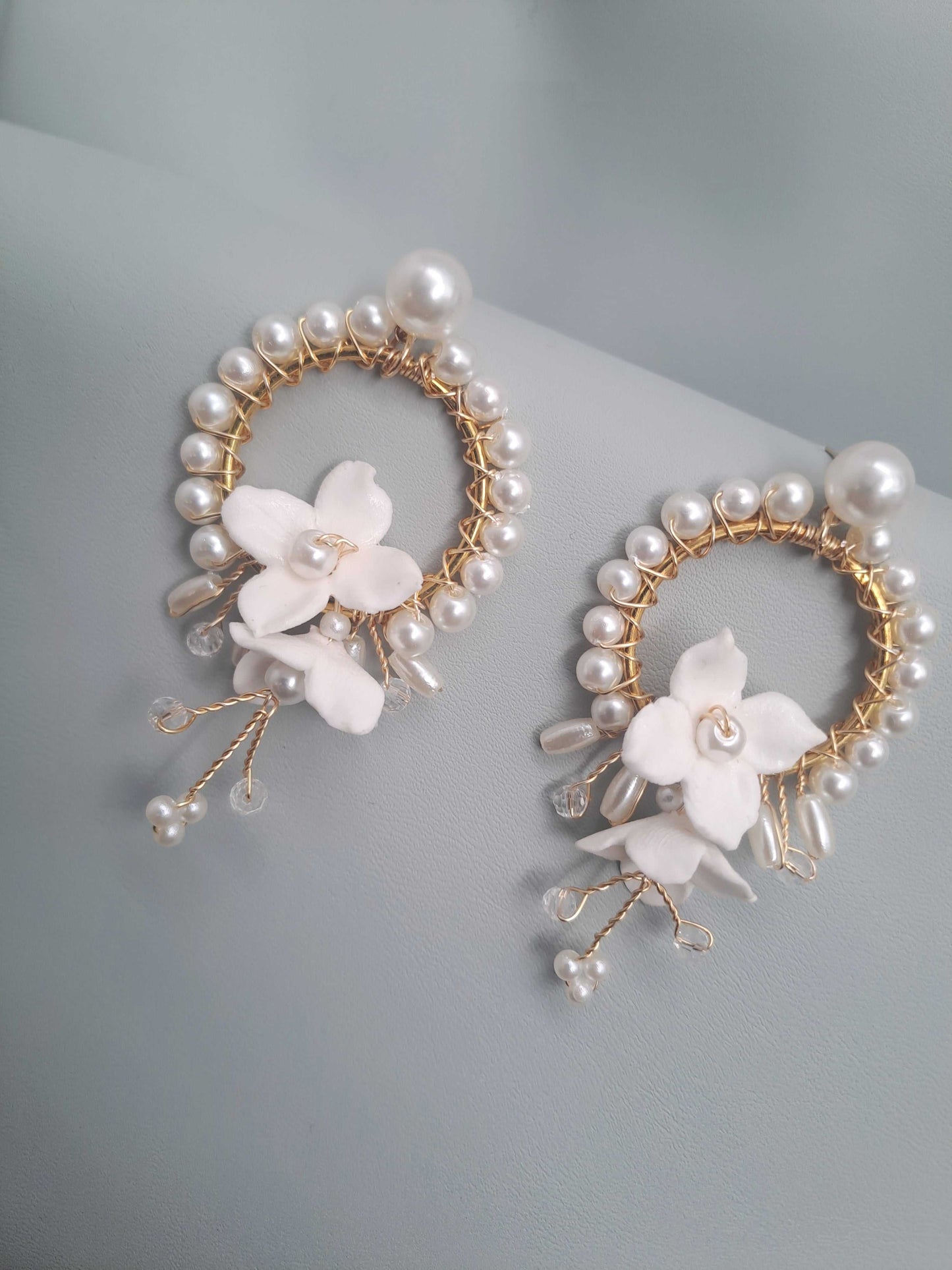 Pair of earrings with pearl and floral design on a light gray background