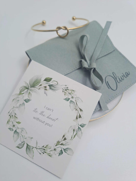 Greeting card with floral design and text, accompanied by a matching envelope and bracelet on a light background.