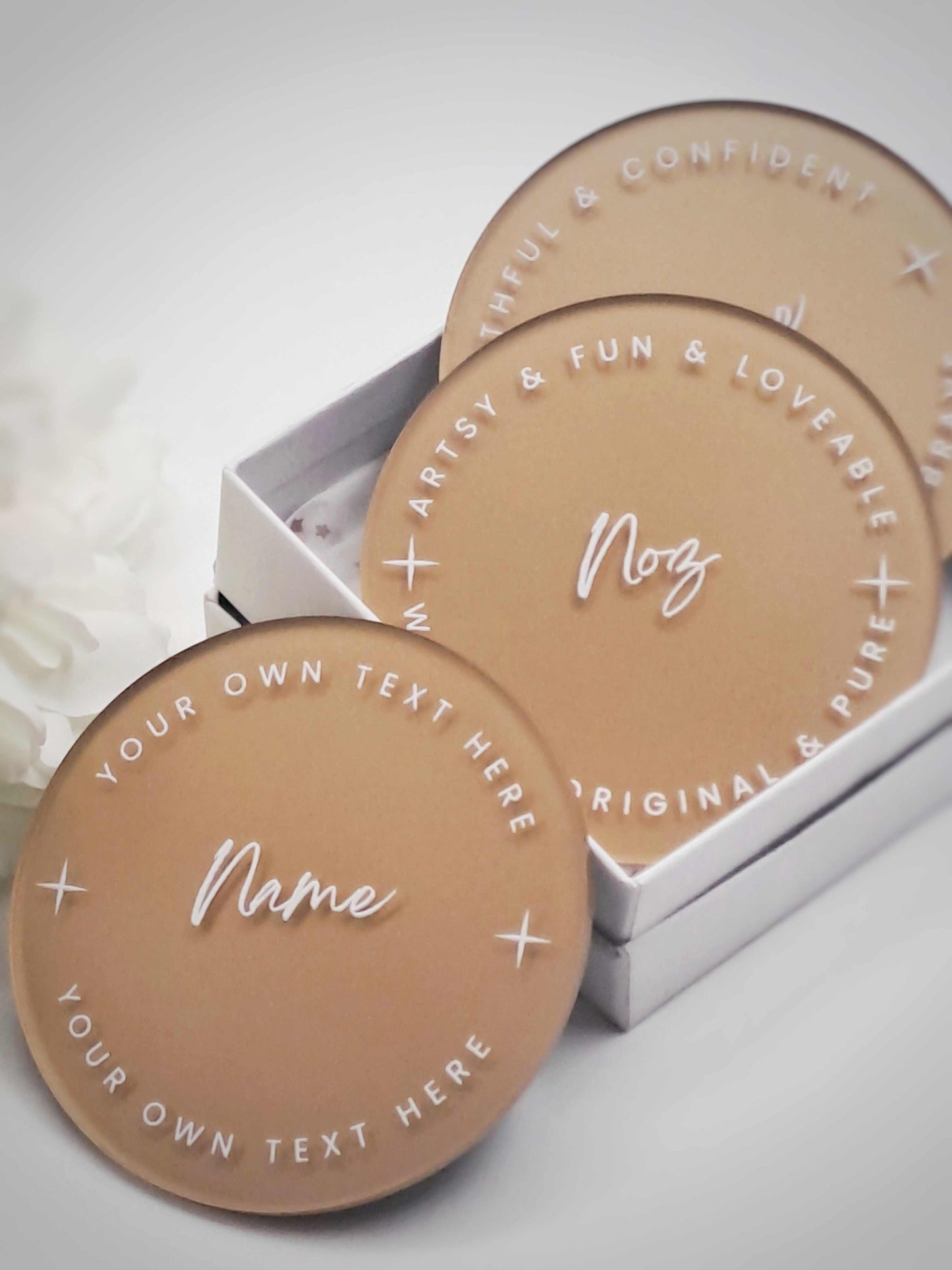 Personalised gold acrylic coaster with custom white text for names and messages, elegant table decor and guest keepsake.