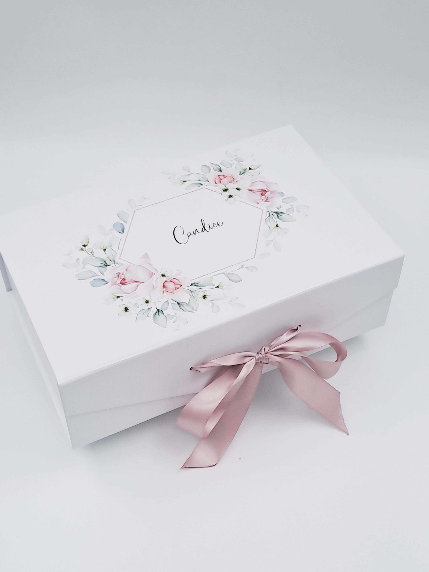 White gift box with floral design and pink ribbon on a white background