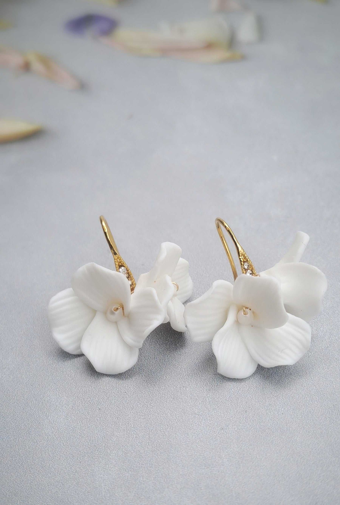 Gold bridal earrings with white ceramic flower dangle design