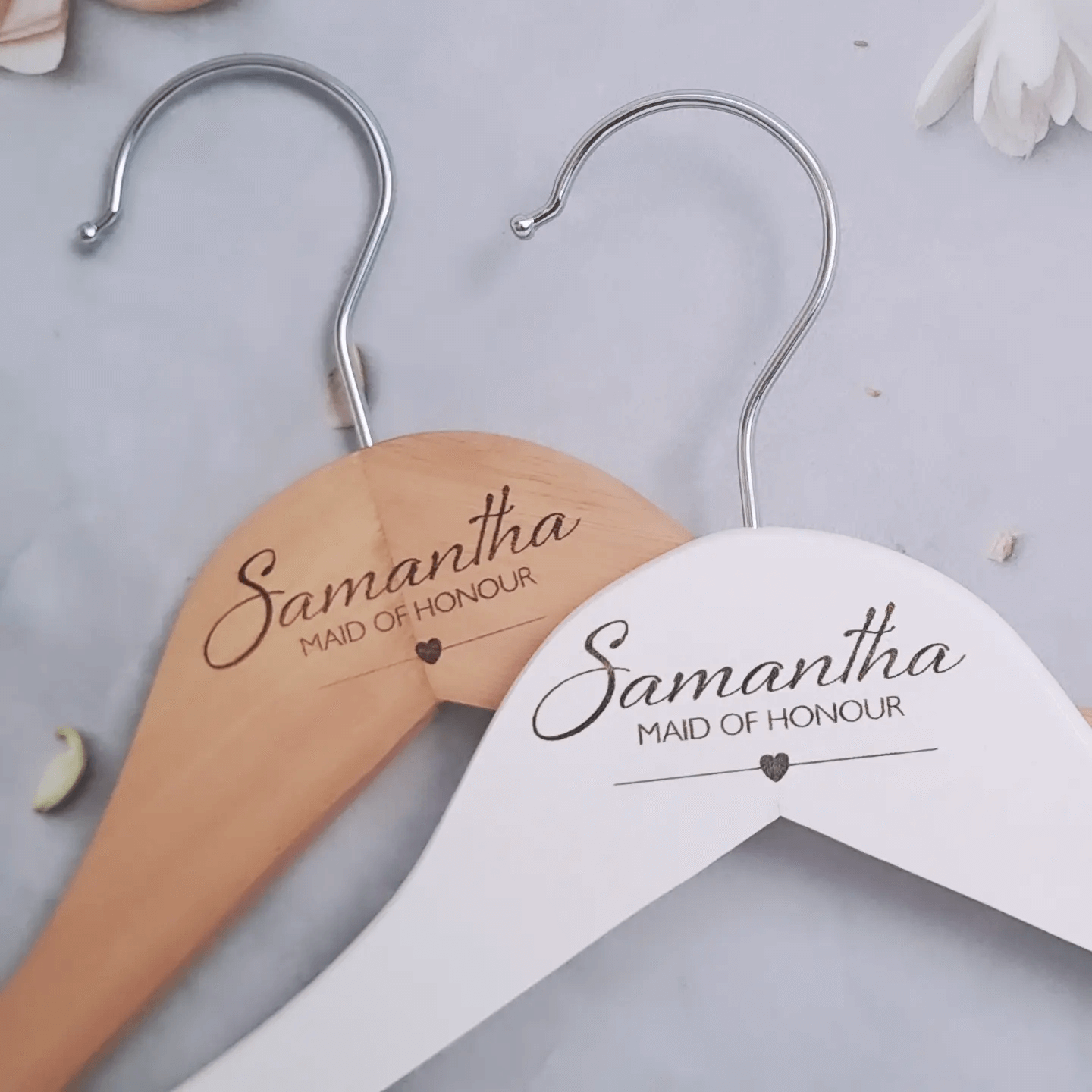 Personalised engraved wooden bridal party hangers with "Samantha Maid of Honour" text and heart detail, available in natural wood and white finishes.
