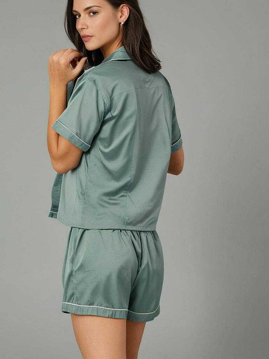 Woman wearing eucalyptus sage green silky satin pajama set with short sleeves and shorts, back view