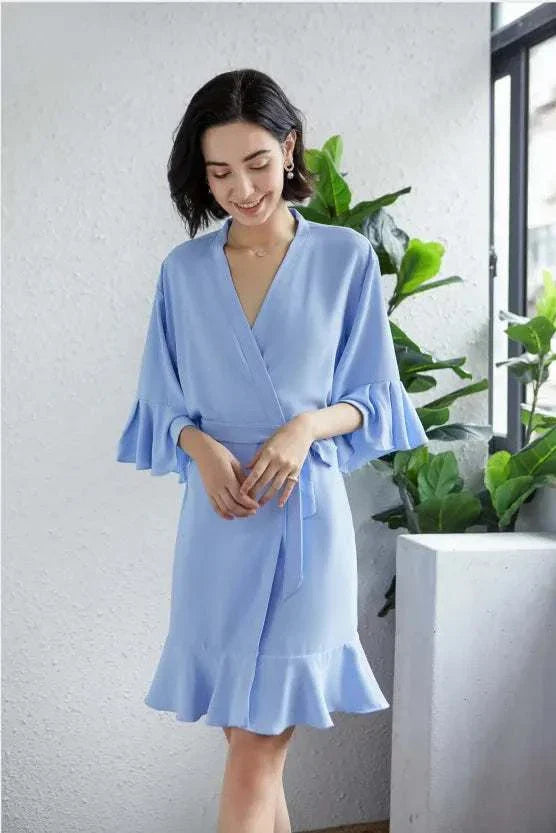 Woman wearing a soft blue ruffle robe with a wrap design and delicate ruffle details.