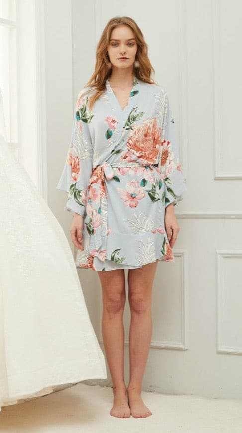 Woman wearing a blue floral cotton gown with lace edge and a waist tie belt.