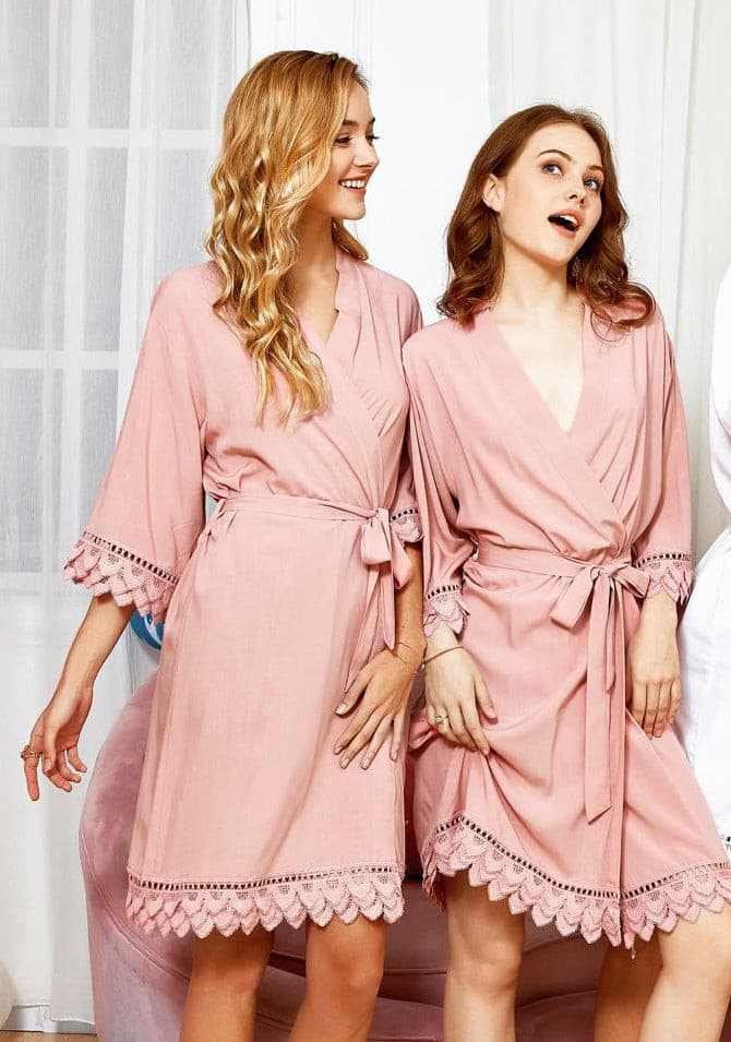 Two women wearing blush cotton gowns with lace edges and waist ties indoors