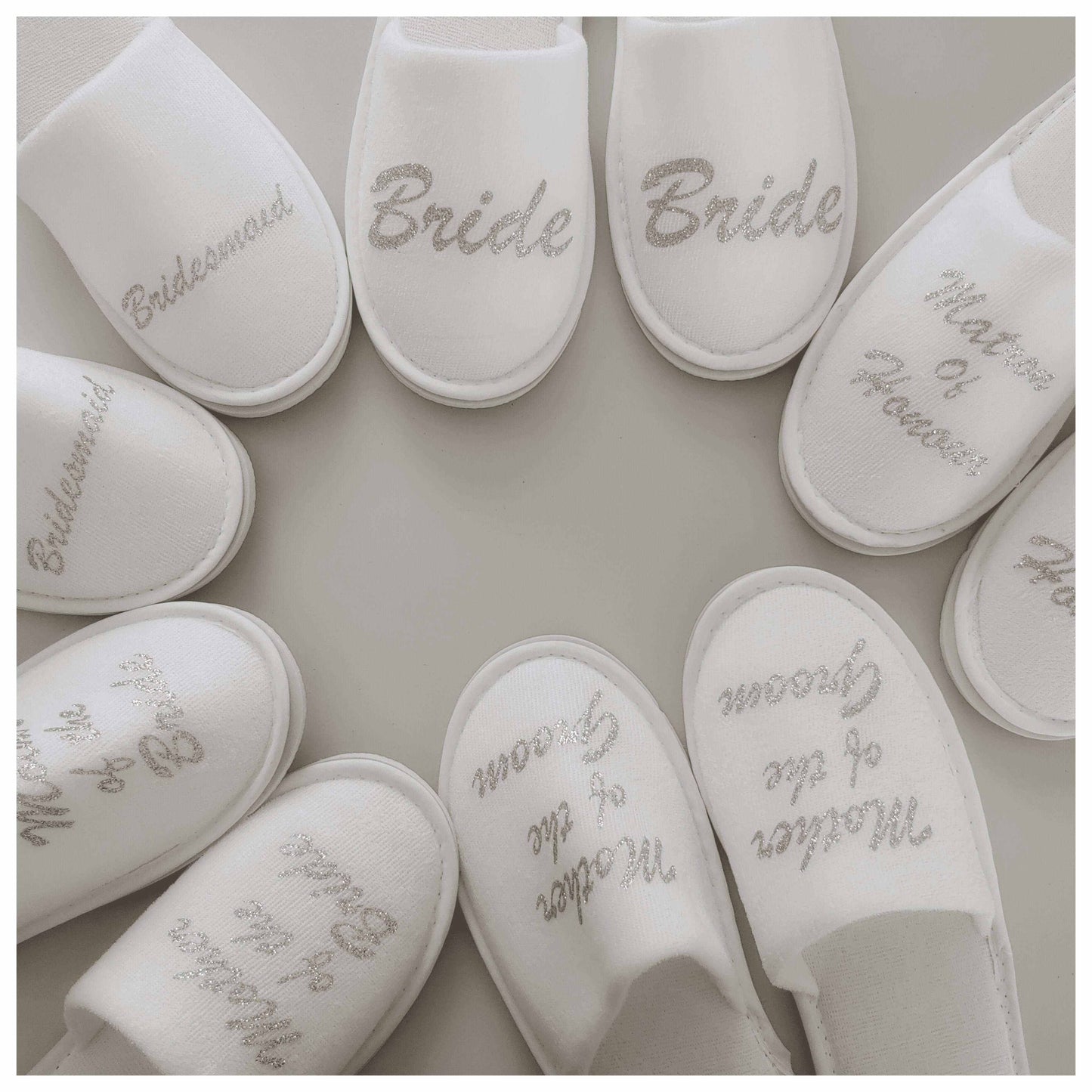 Closed toe bridal party slippers with wedding titles in a circle on a neutral background