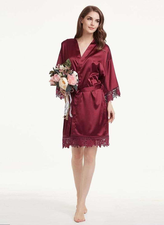 Woman wearing a soft burgundy satin and lace robe holding a bouquet, perfect for bridal party.