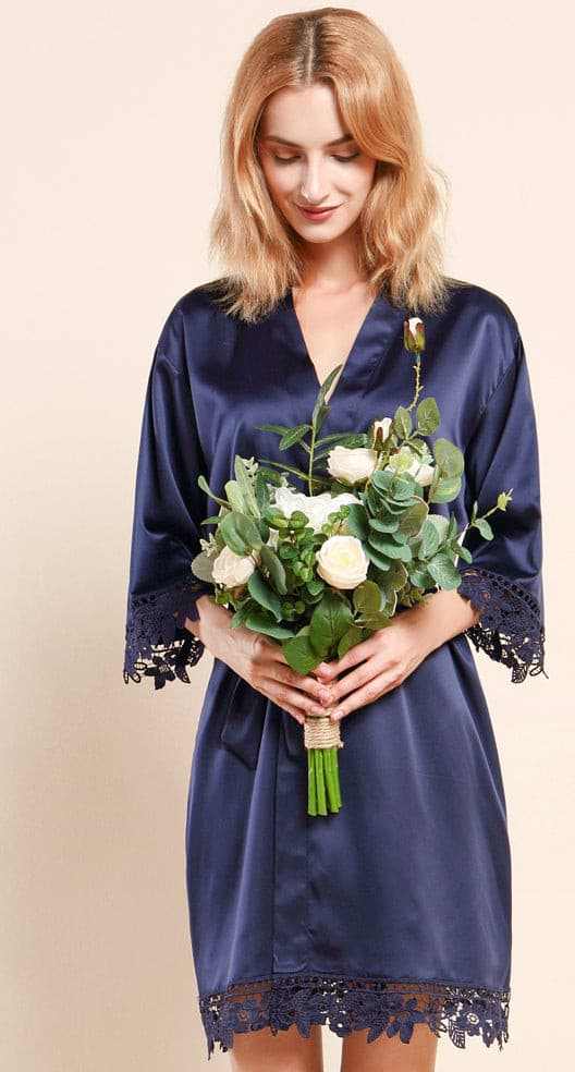 Woman wearing navy satin robe with lace edges holding a bouquet of flowers