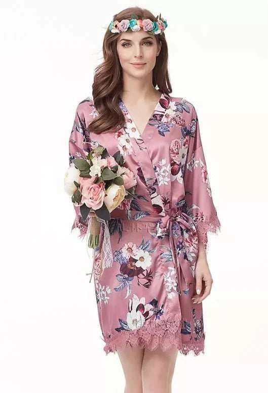 Rose pink satin robe with floral print and lace trim, styled for bridal party preparation.