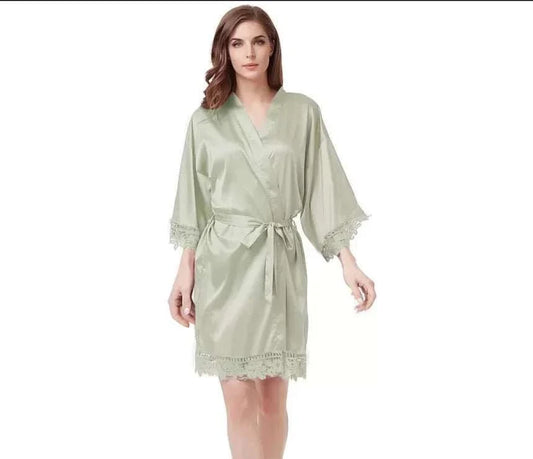 Woman wearing sage satin robe with lace trim and waist tie belt