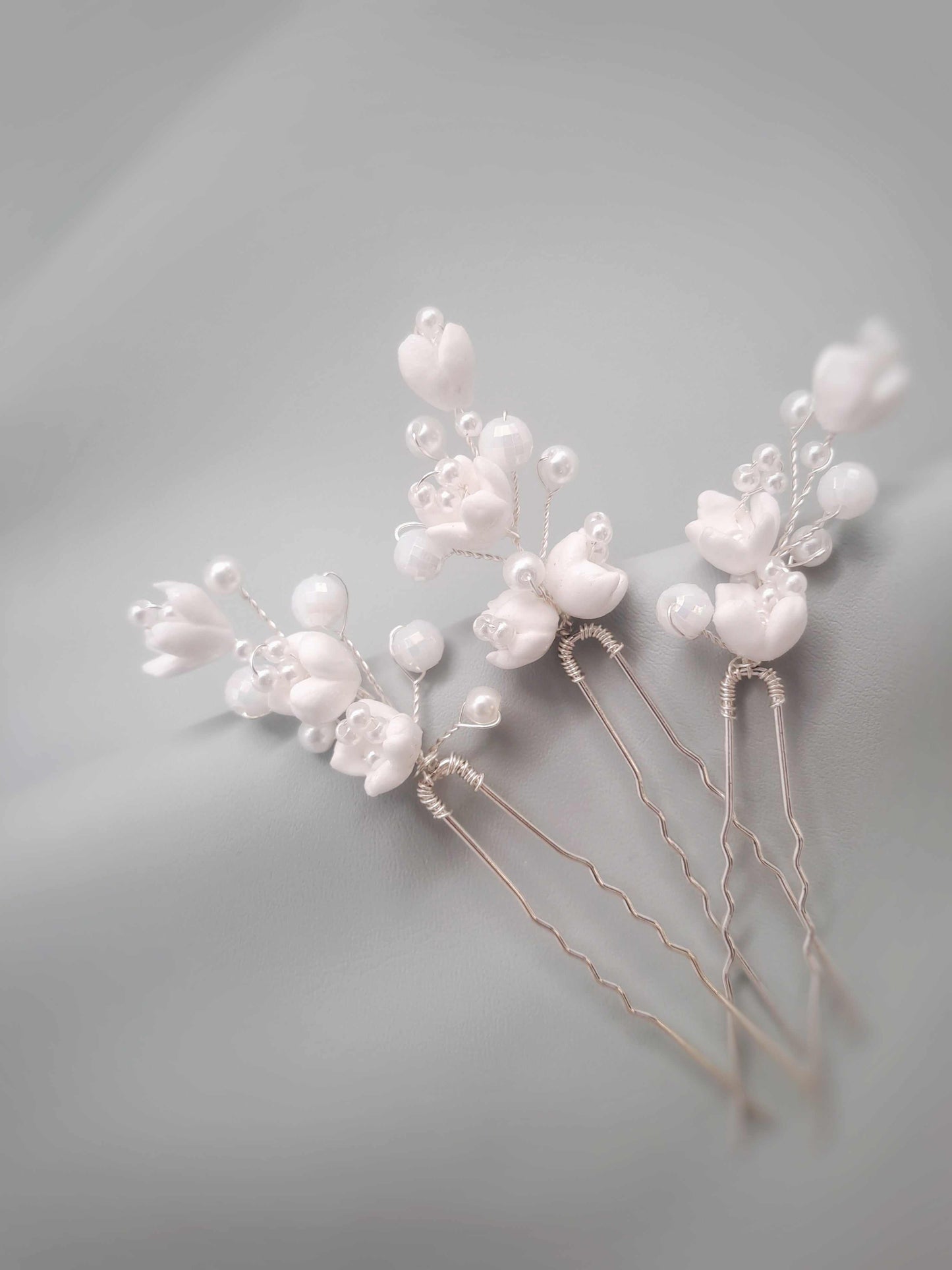 Three pearl hairpins on a light gray background