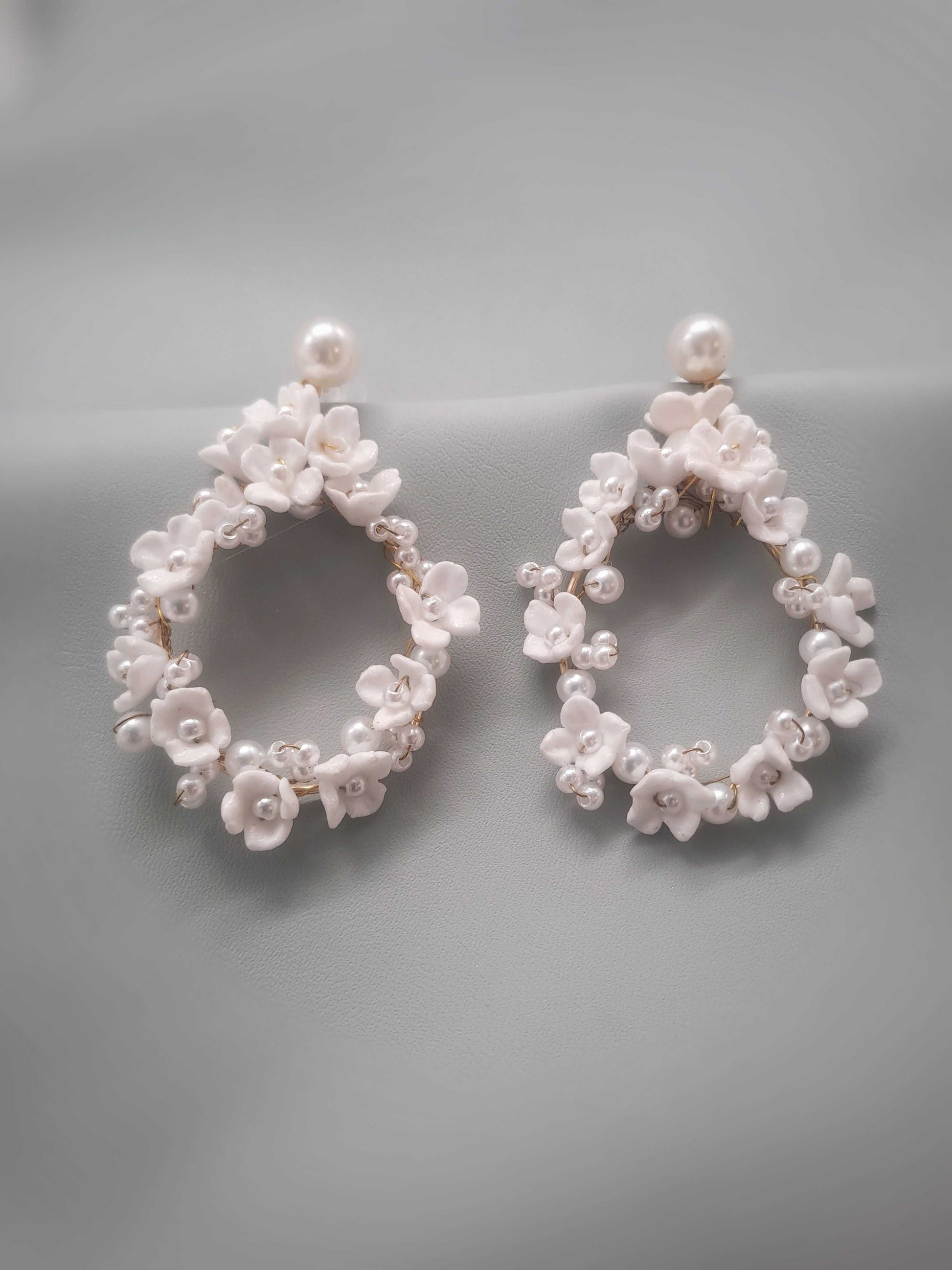 Pair of pearl and floral hoop earrings on a gray background