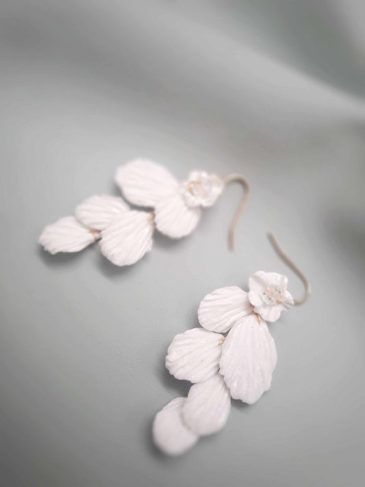 White floral earrings on a gray background