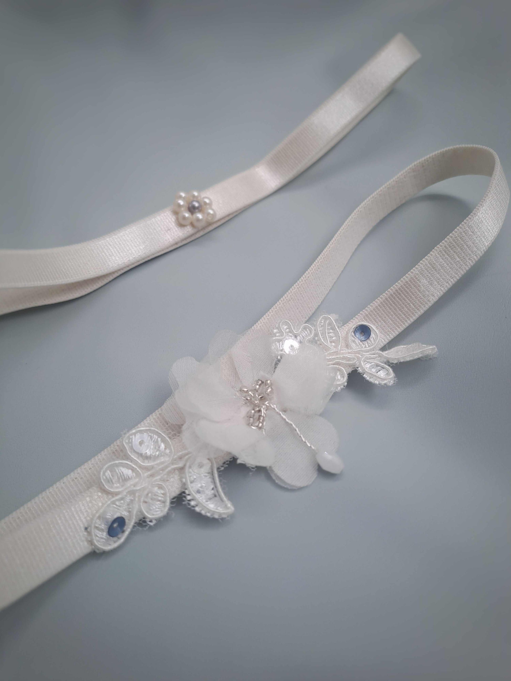 White garter set ith floral and lace details on a gray background