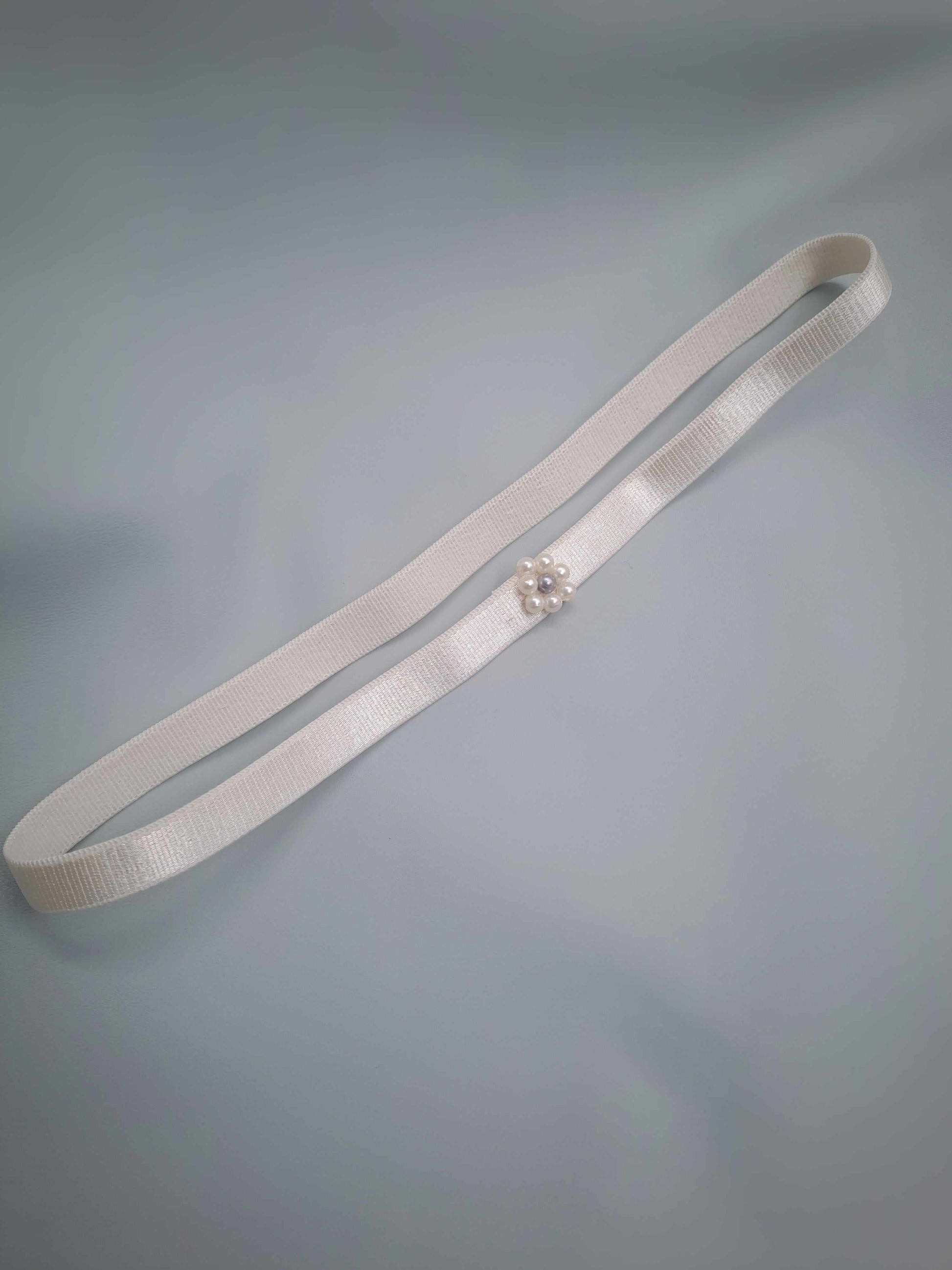White garter with apearl embelishment on a gray background