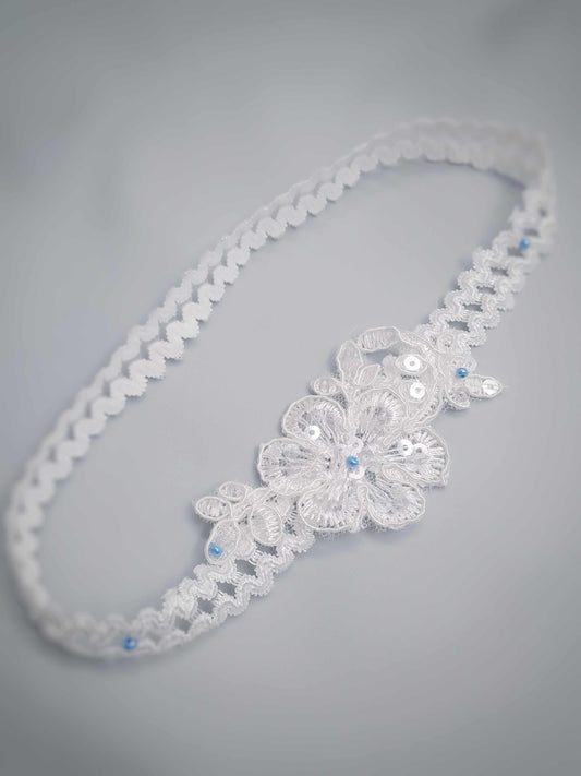 Lace garter with floral design and blue beads on a gray background