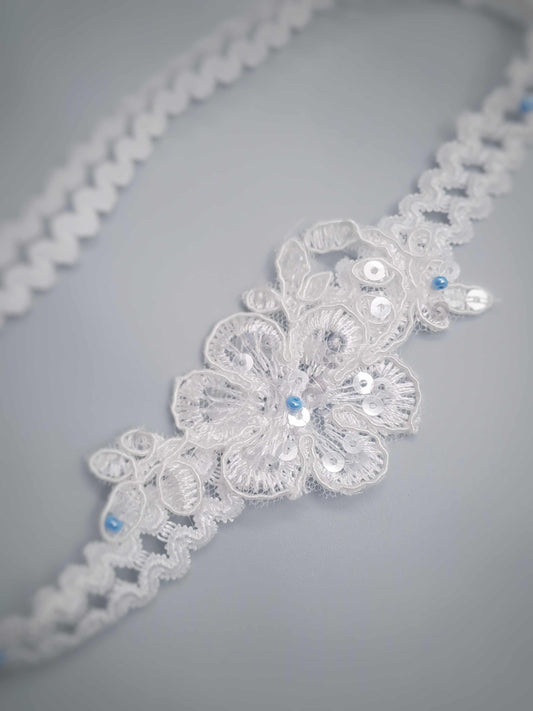 Lace garter with floral patterns and sequins on a gray background