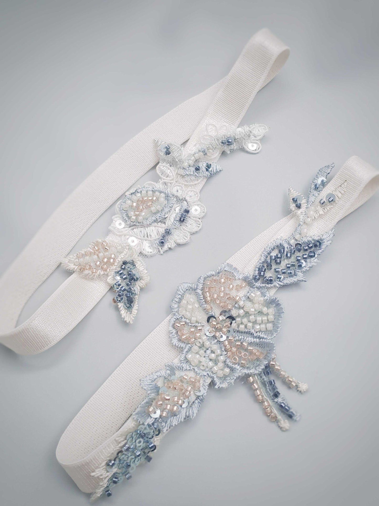 Wedding garter set with floral patterns and sequins on a gray background