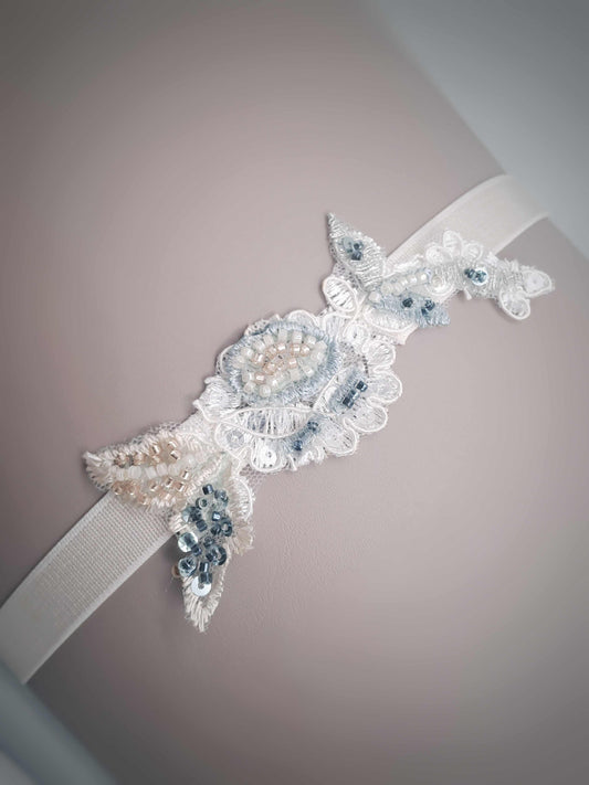 Hand beaded Aspen wedding garter with sage, blue, and champagne beads on white elastic band