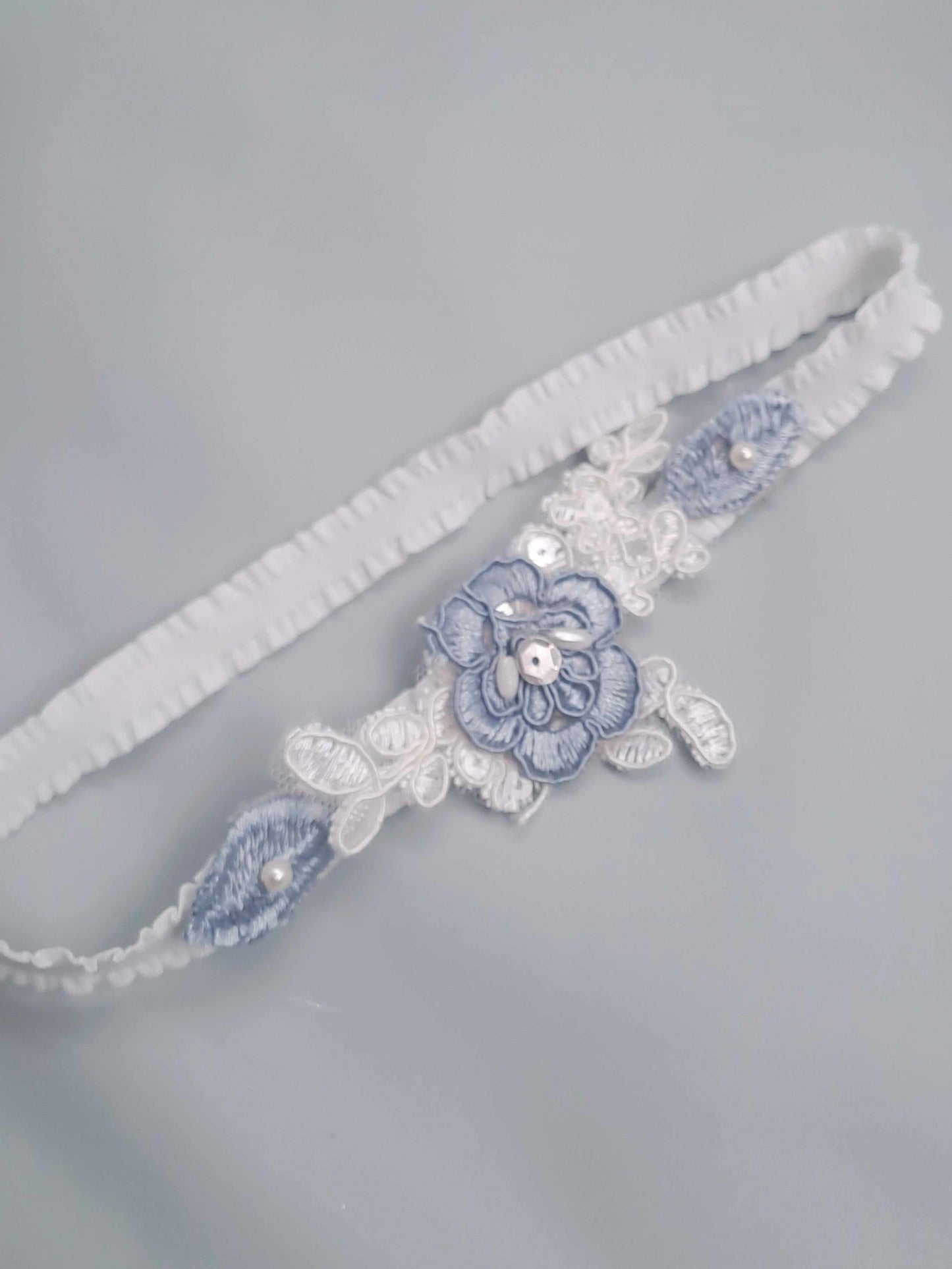 White garter with blue floral design on a gray background