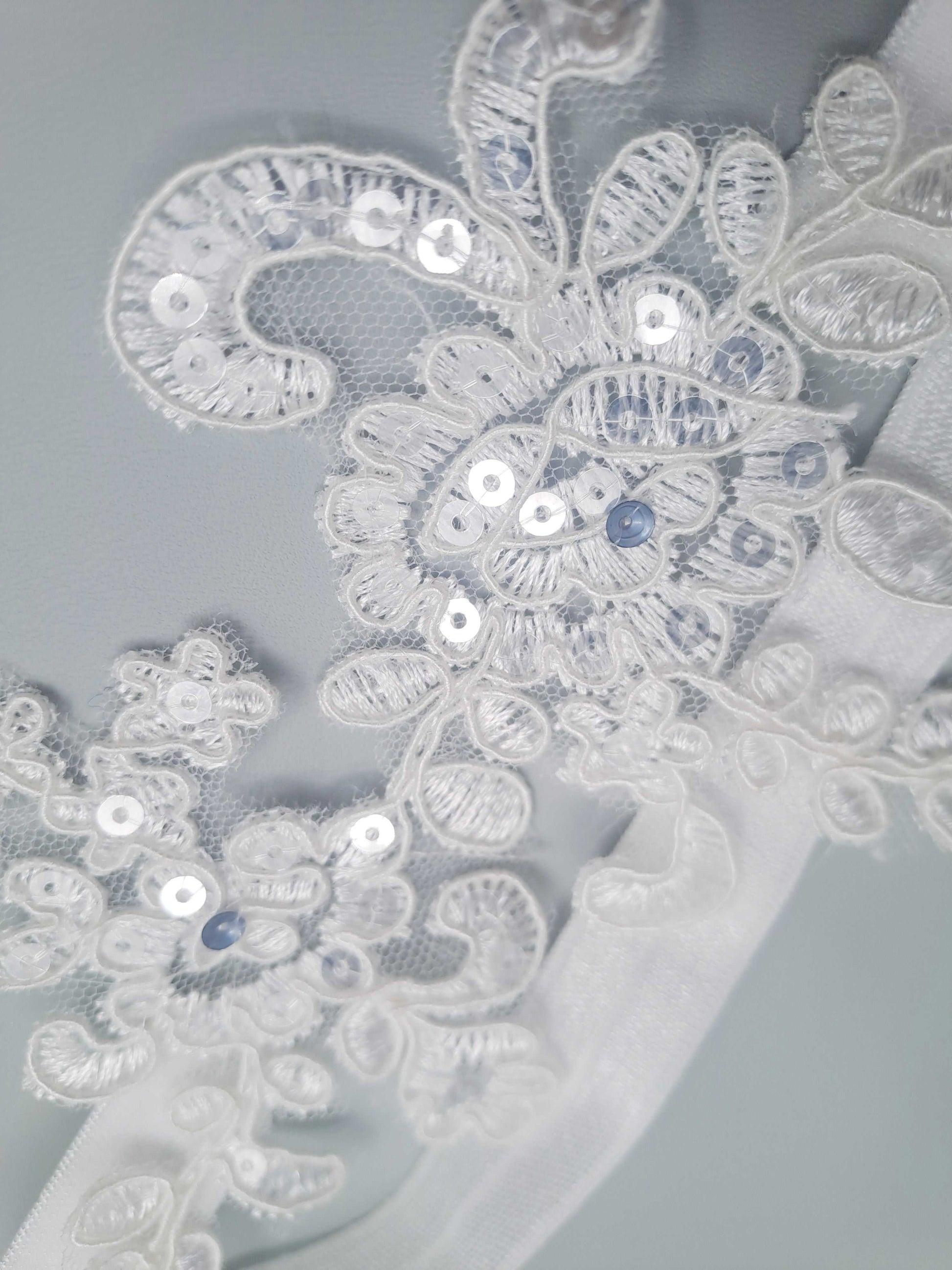 Close-up of intricate lace with sequins on a light gray background