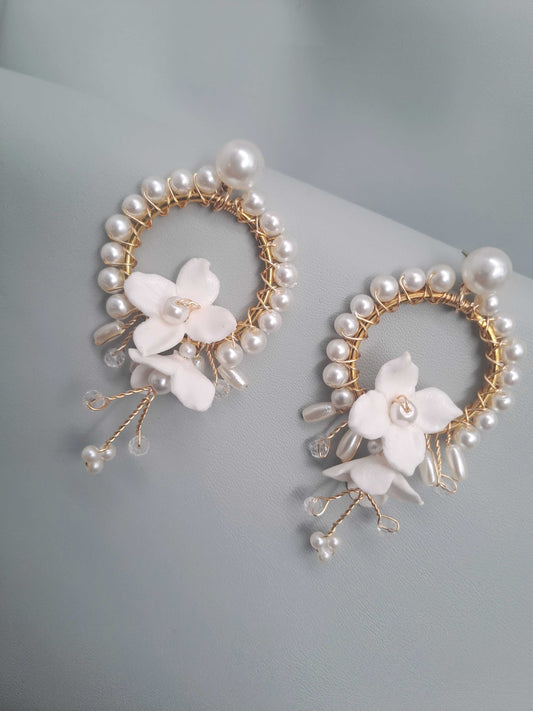 Pair of earrings with pearl and floral design on a light gray background