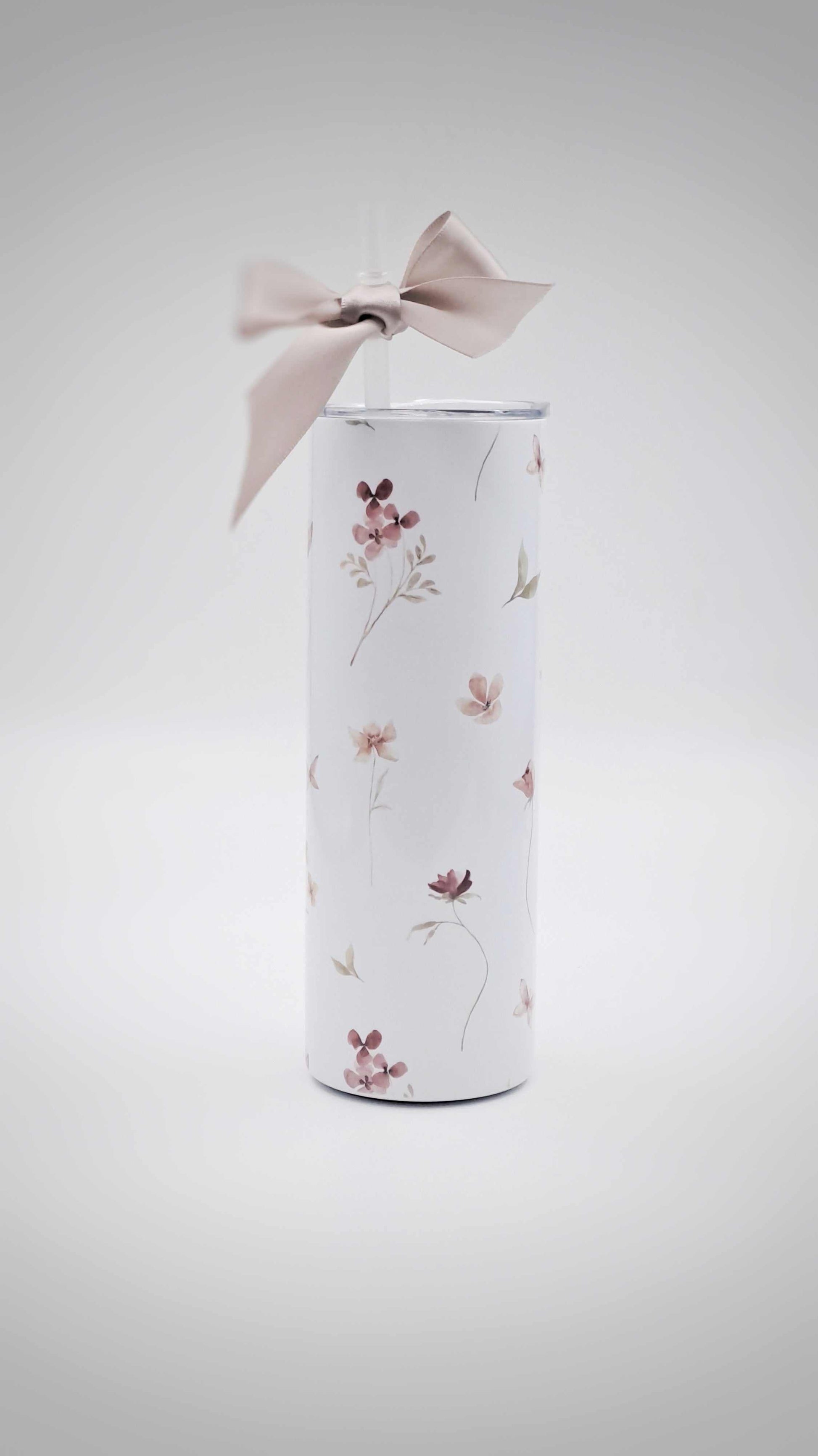 Personalised stainless steel tumbler with floral design and a bow on a light gray background