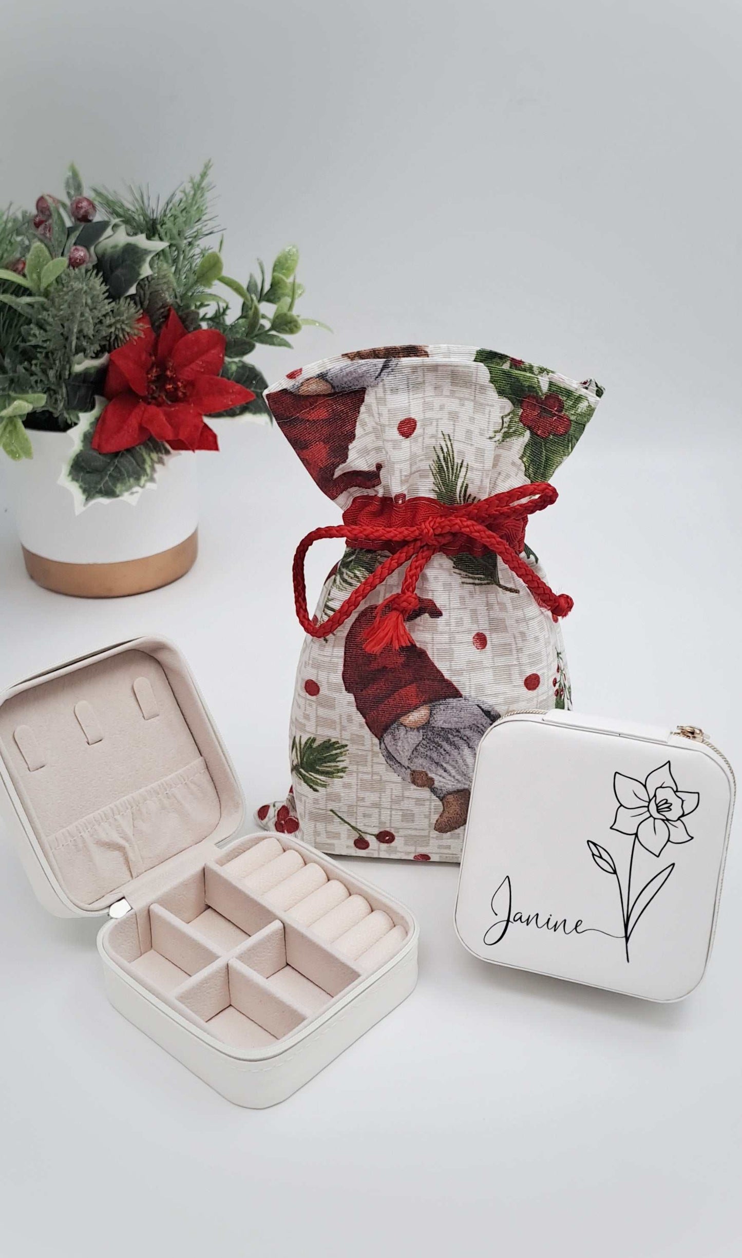 Decorative gift bag with red ribbon, jewelry box, and pouch on a light background