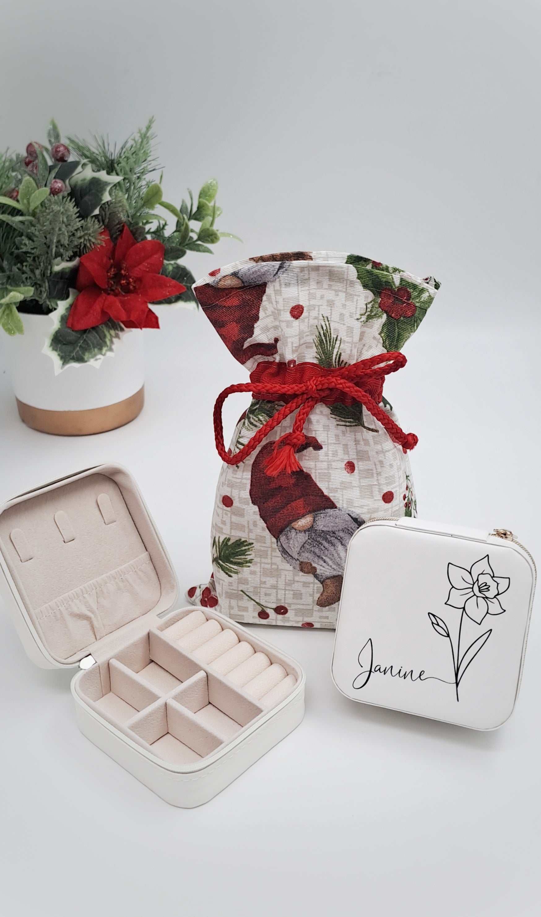 Decorative gift bag with red ribbon, jewelry box, and pouch on a light background