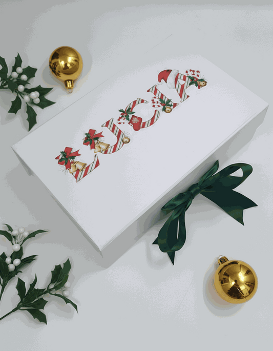 White personalised christmas gift box with festive design and green ribbon on a light gray background