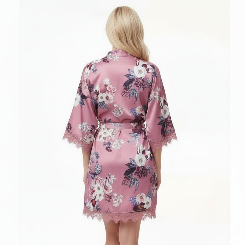 Back view of a rose pink satin robe with floral print and lace trim worn by woman with blonde hair