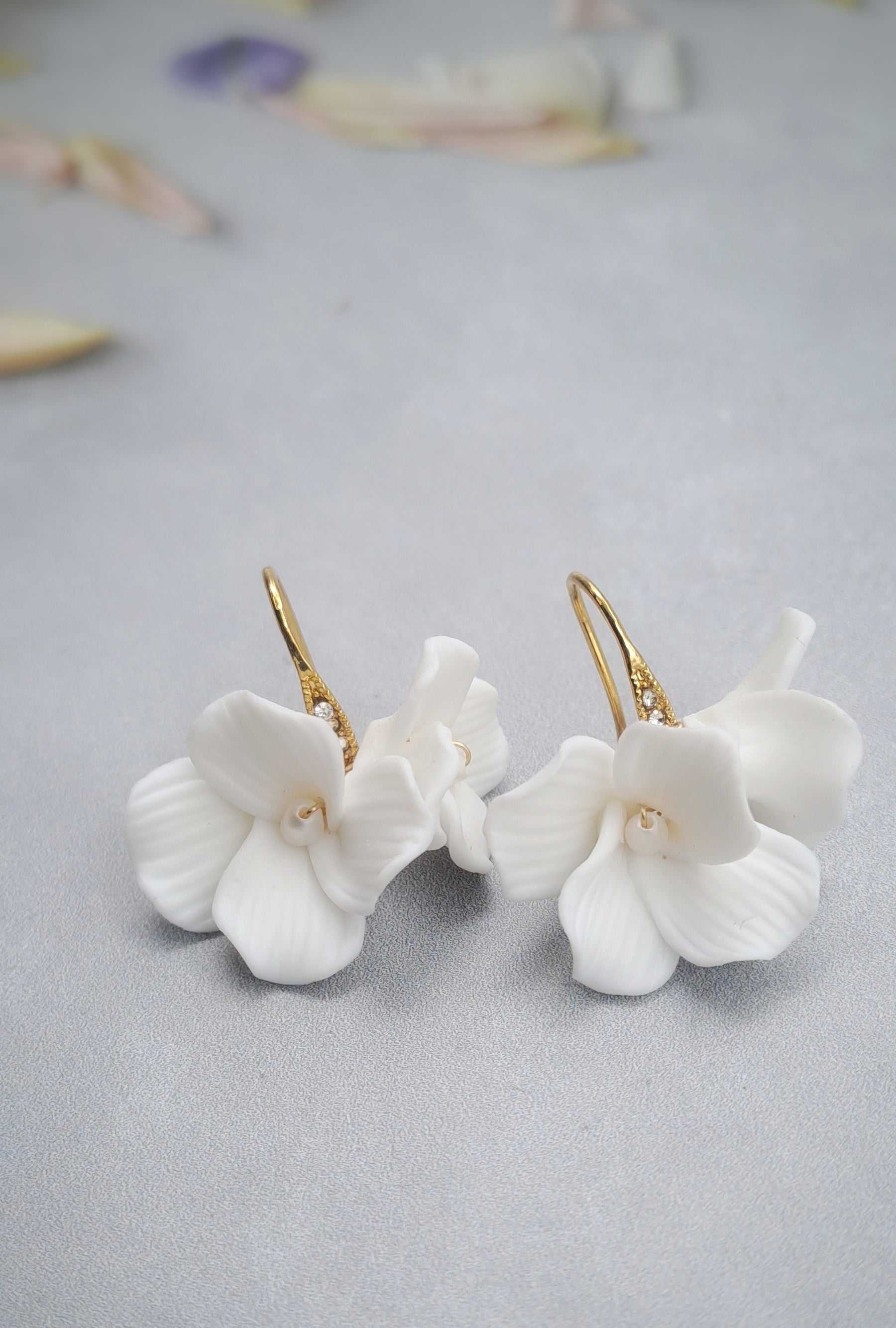 Gold bridal earrings with white ceramic flower dangle design