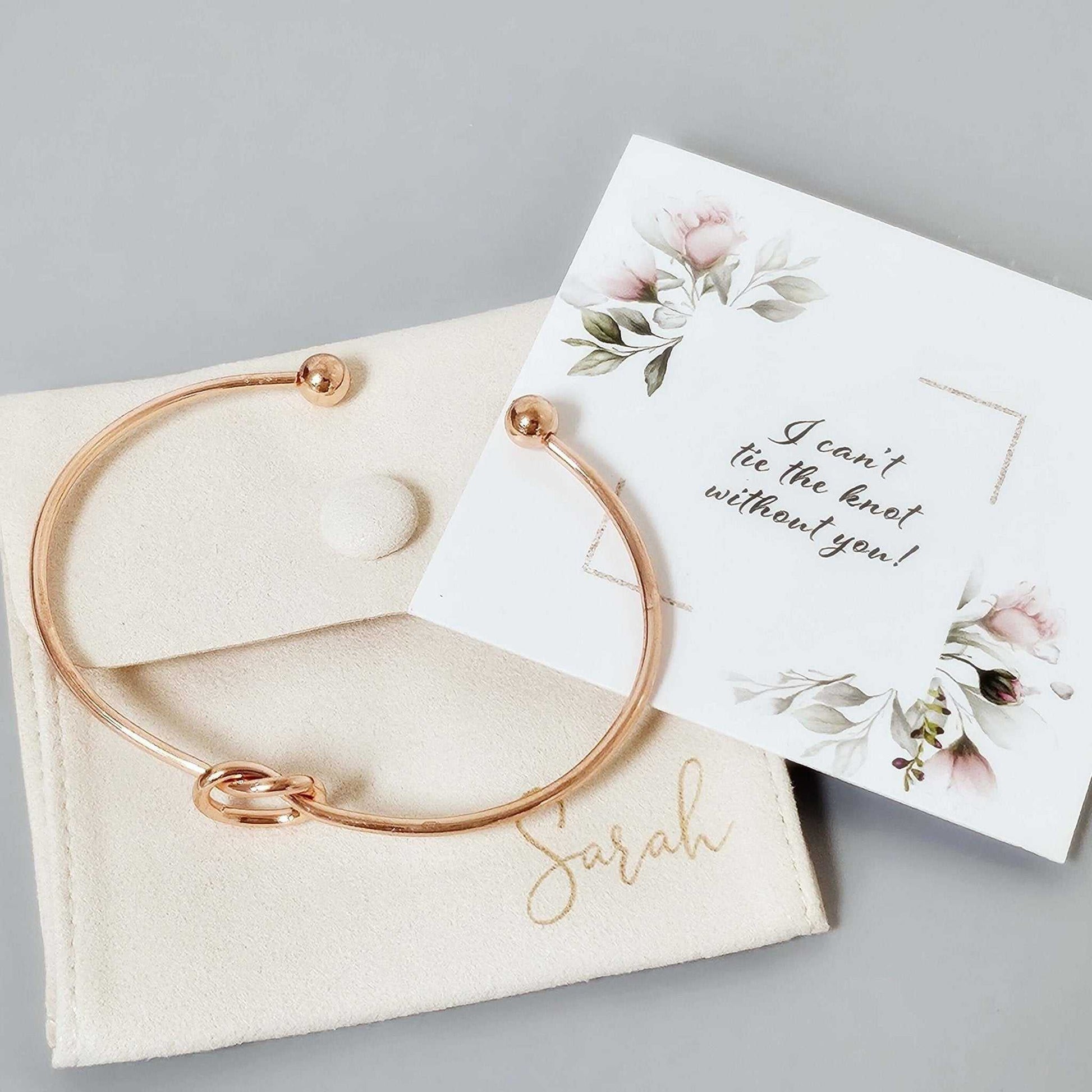 Rose gold bridesmaid proposal bangle with personalized suede pouch and floral note saying "I can't tie the knot without you"