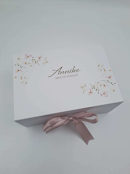 White box with floral design and pink ribbon on a light gray background