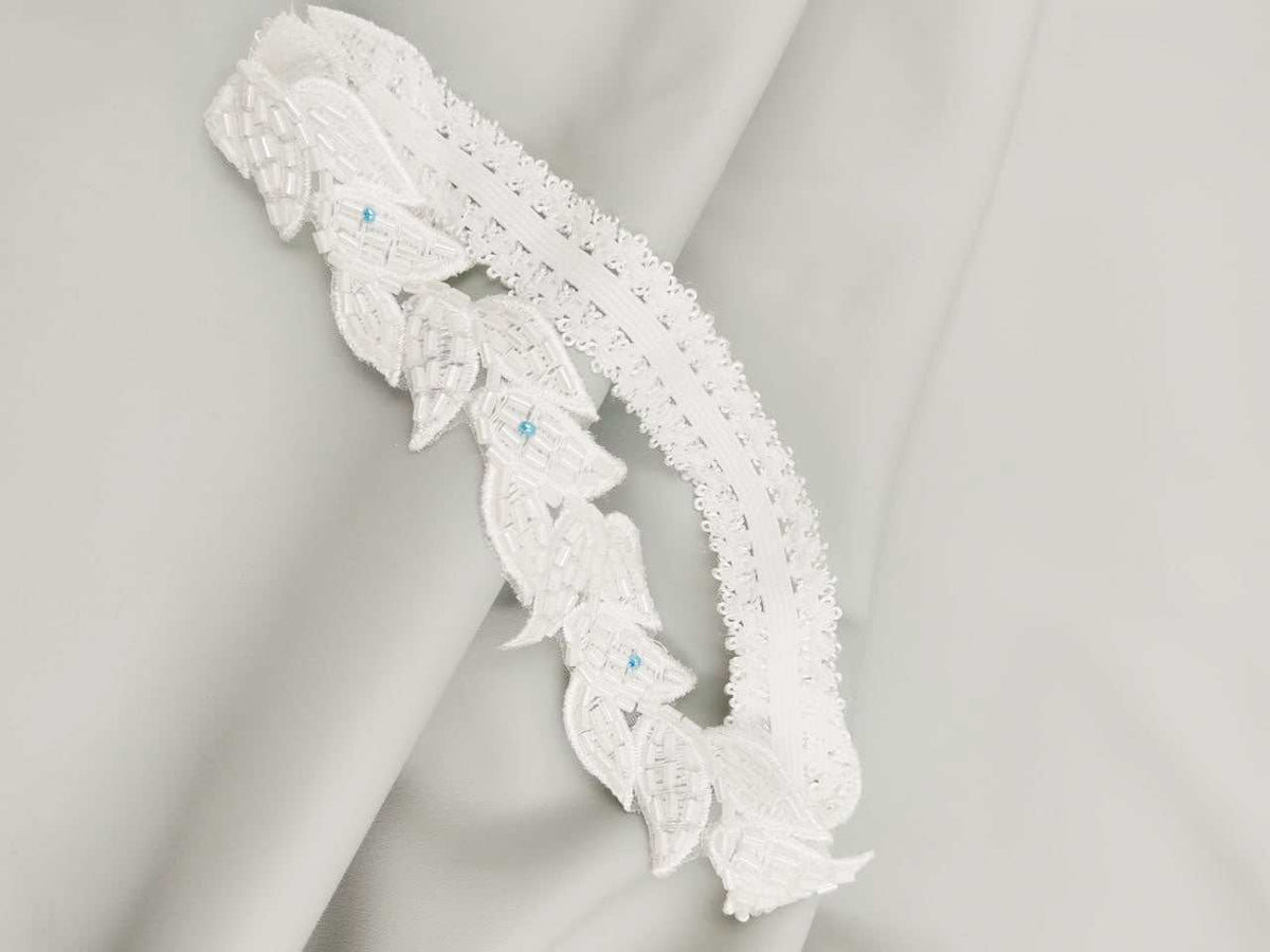 Zarina white and blue garter in white lace with embroidered leaf motifs and small pale blue bead accents.